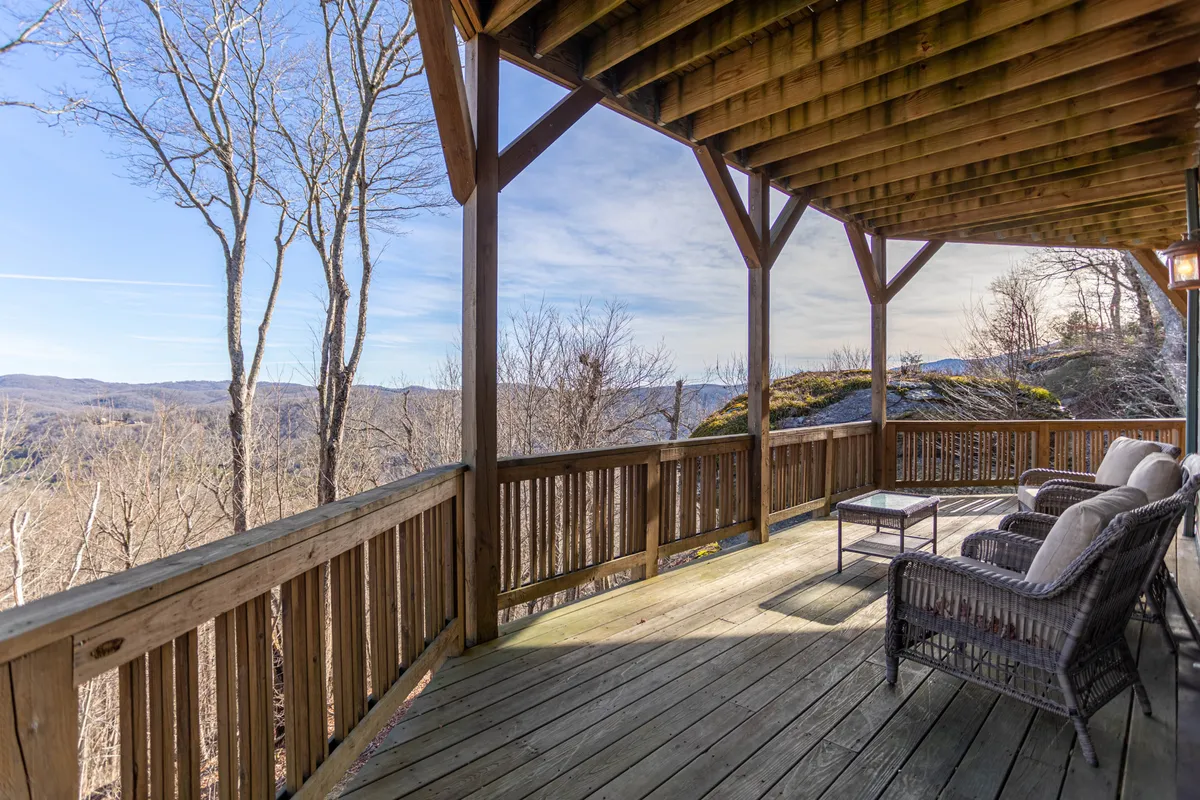 A serene wooden deck set against a sweeping mountain landscape, featuring comfortable seating ideal for relaxation or socializing. The openness of the deck highlights the expansive vistas and the sense of peace the High Country offers.