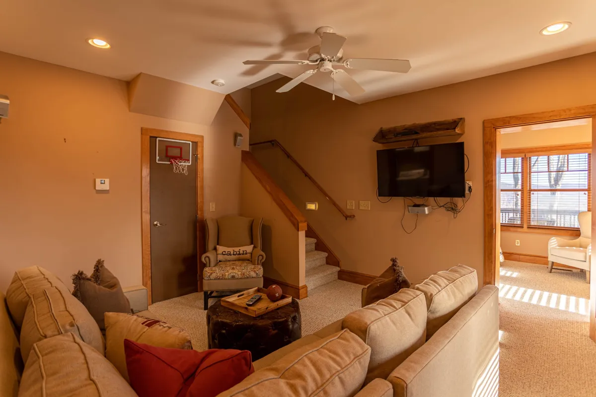 A playful and casual family room featuring a large sofa, armchair, television, and a basketball hoop on the wall. The relaxed setup is perfect for watching TV, enjoying games, or family gatherings, creating a fun, multi-functional entertainment space.